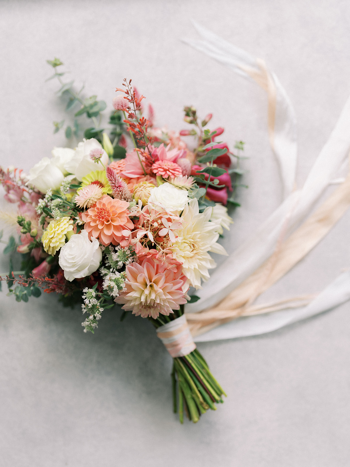 Bridal bouquet of dahlias, roses and eucalyptus, tied with ribbon
